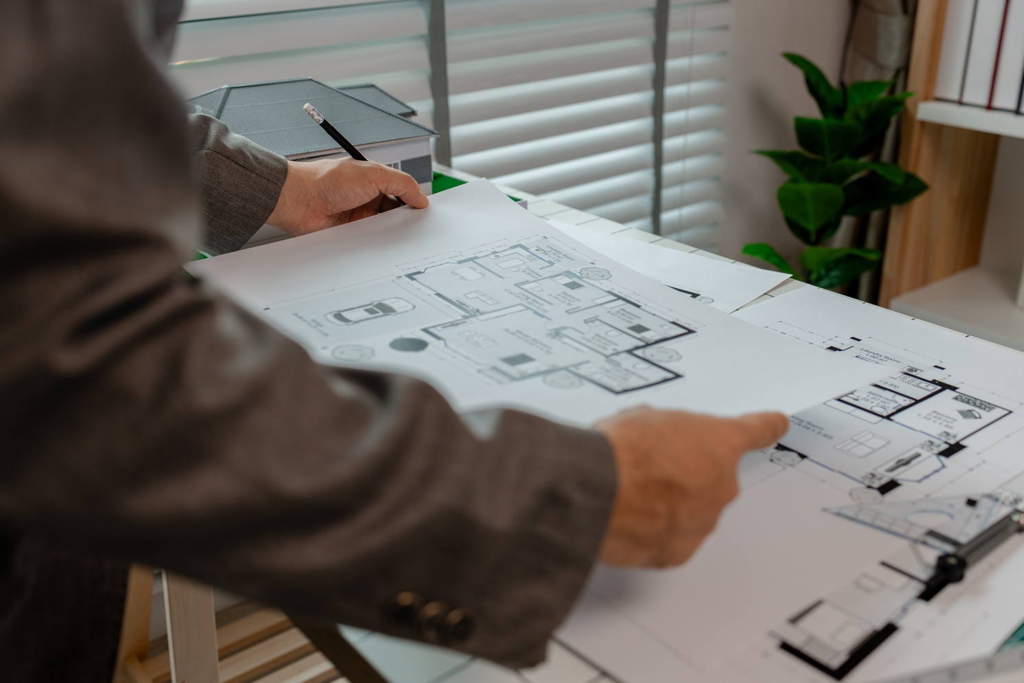 Architekt prüft Bauplan und Grundriss eines Hauses zur Planung der Bauzeit